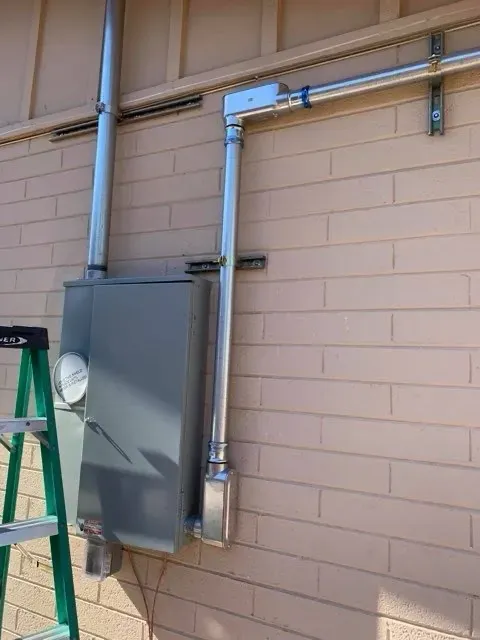 New service panel with rigid conduit installed on a block wall - Orozco Electric