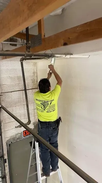 Electrician installing conduit and lighting in a warehouse ceiling - Orozco Electric